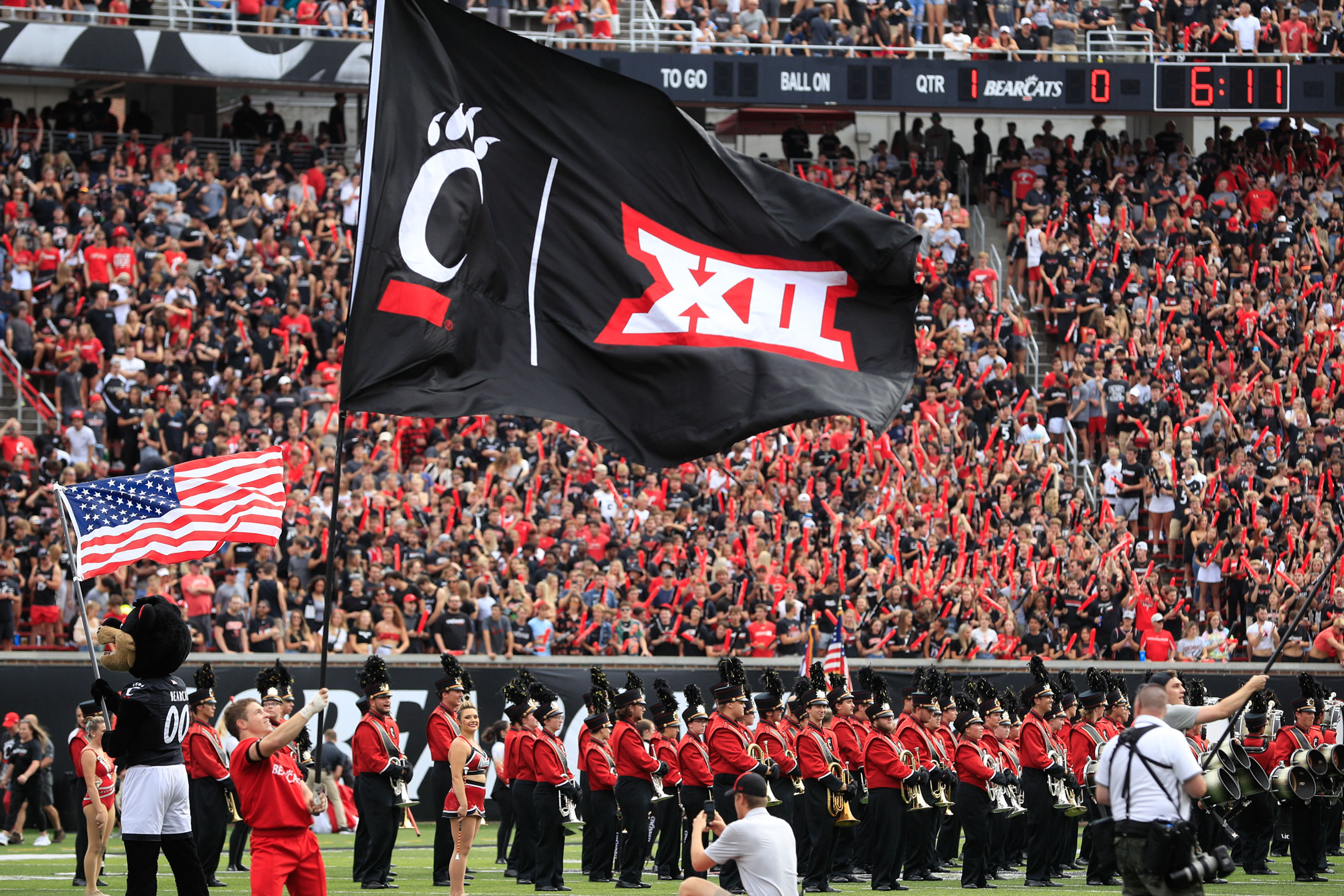 A University of Cincinnati cheerleader carries a Big XII flag